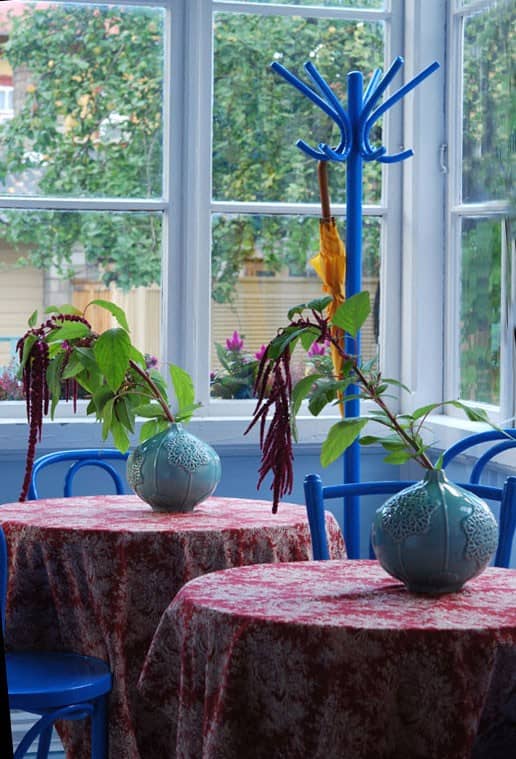 Veranda lauad taimevaasidega ja sinised toolid akende ees